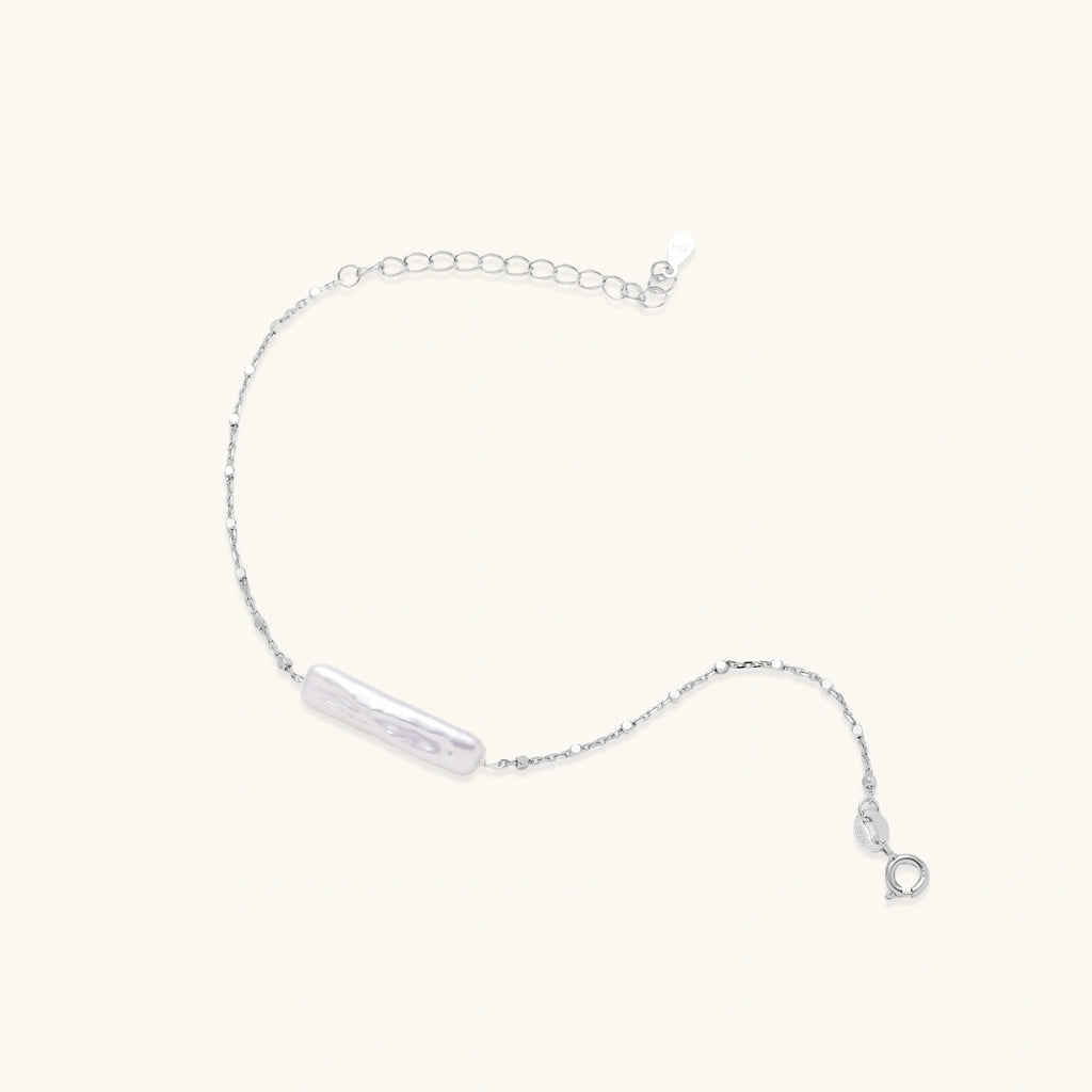 Minimalist bracelet with iridescent baroque pearl on rhodium-plated sterling silver chain against cream background