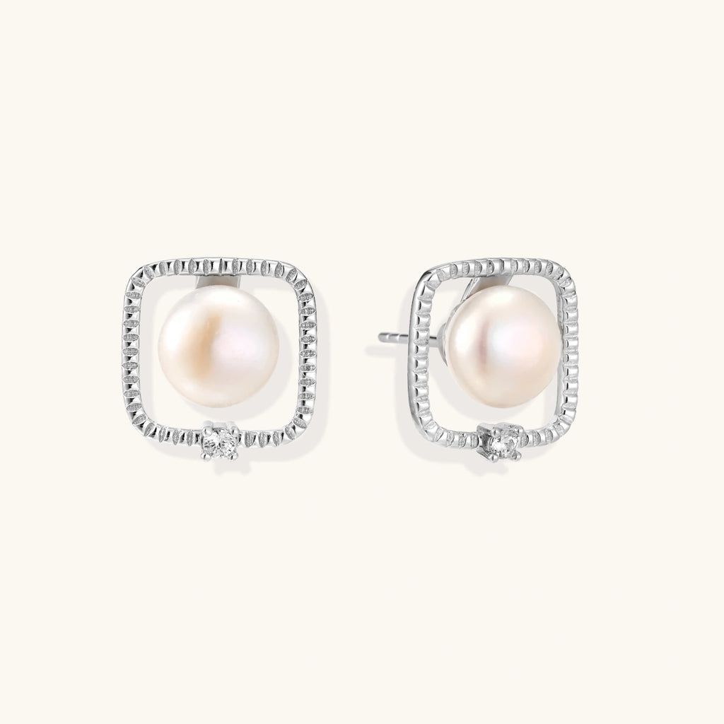 Rhodium-plated silver stud earrings with cushion frame, centered freshwater pearl, and tiny crystal accent