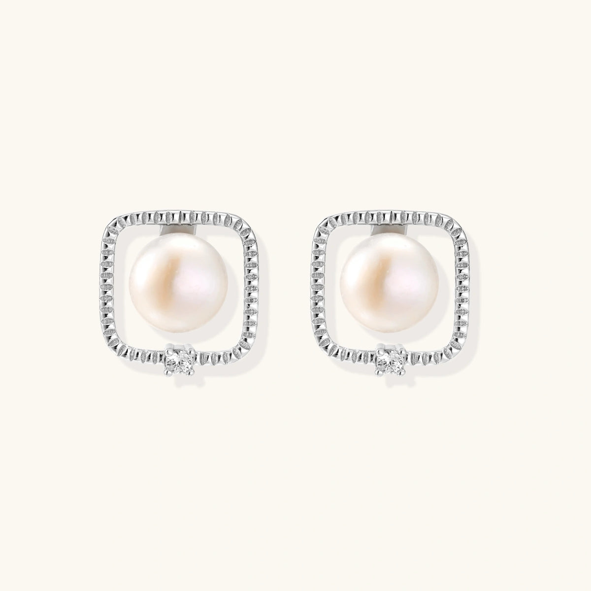 Rhodium-plated silver stud earrings with cushion frame, centered freshwater pearl, and tiny crystal accent