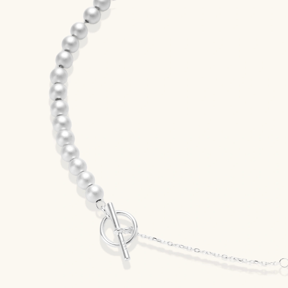 Long sterling silver beaded necklace with graduated sphere design, toggle clasp, and delicate chain extension on white background