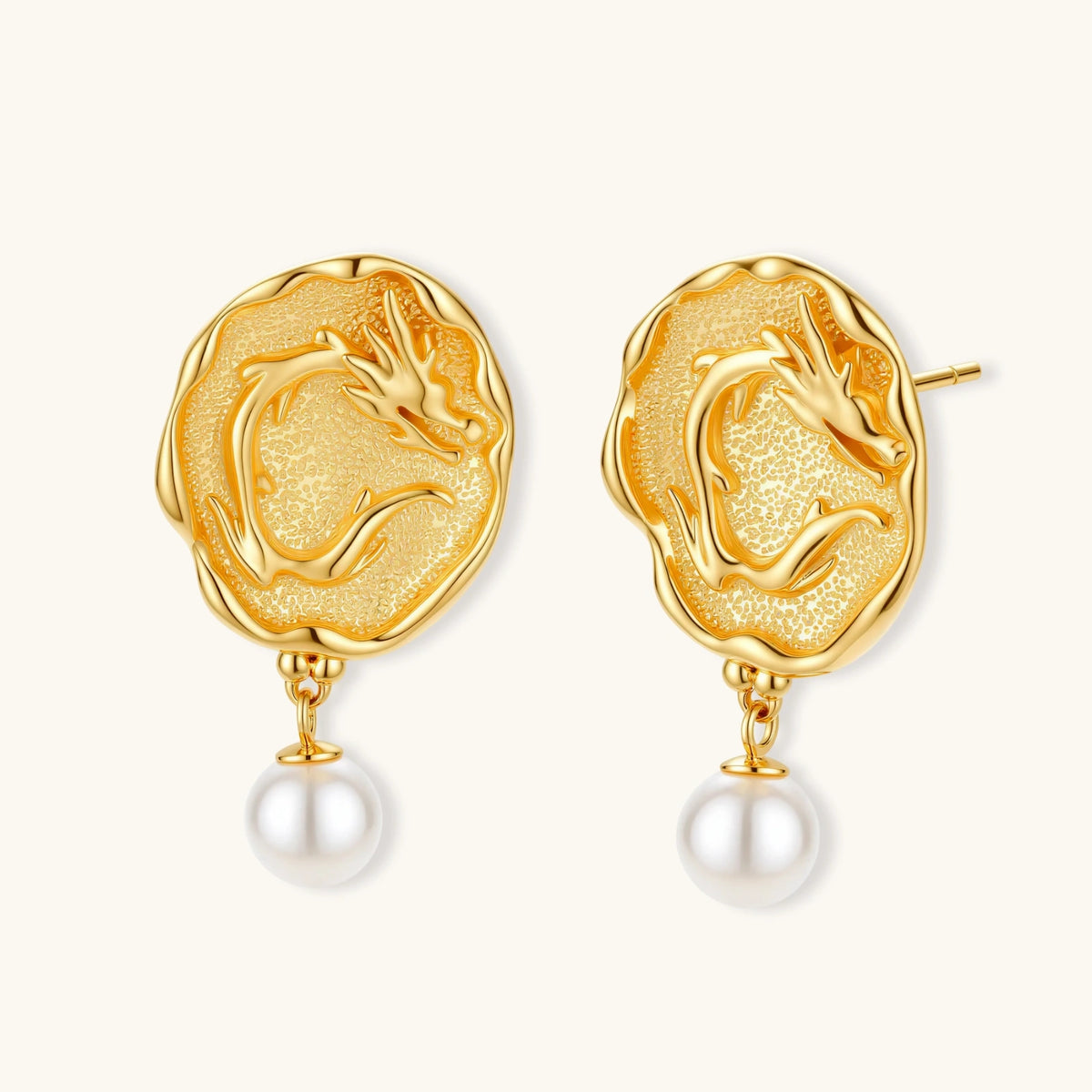 Ornate gold-plated dragon medallion earrings with white shell pearl drops on beige background, featuring detailed Chinese motifs.